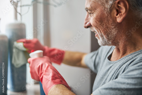Careful senior gentleman cleaning vases in his apartment