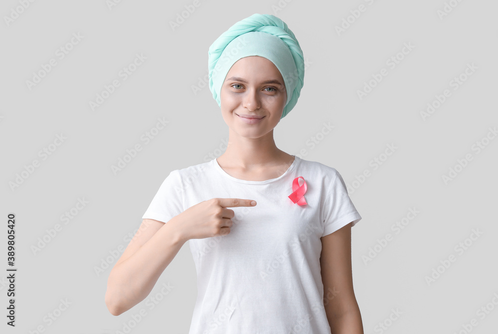 Woman after chemotherapy with pink ribbon on grey background. Breast cancer awareness Woman after chemotherapy with pink ribbon on grey background. Breast cancer awareness