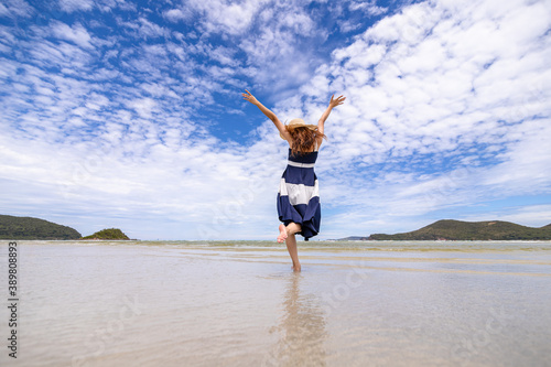 Woman barefoot walking on summer along wave of sea water and sand on the beach.