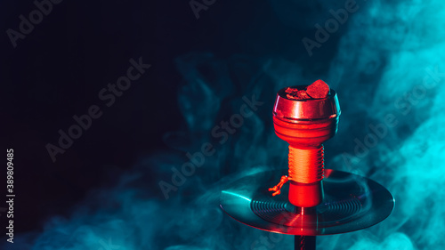 hot red coals for hookah shisha in a metal bowl with smoke on a color background with a copy space