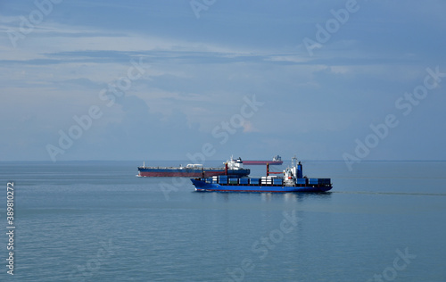 Cargo ships sailing through the cam, blue sea. 