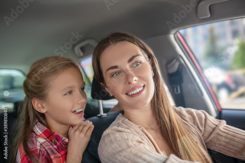 Smiling daughter talking to her mom from backseat of car