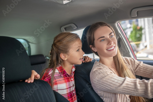 Happy daughter talking to her mom from backseat of car