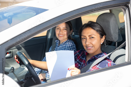 Portrait of smiling Peruvian woman driving car, holding blank white paper with copyspace © JackF