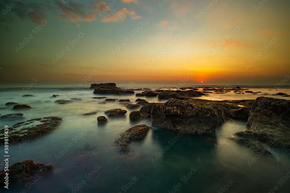 Obraz premium Amazing seascape. Landscape background. Beach with rocks and stones. Low tide. Motion water. Slow shutter speed. Soft focus. Mengening beach, Bali, Indonesia