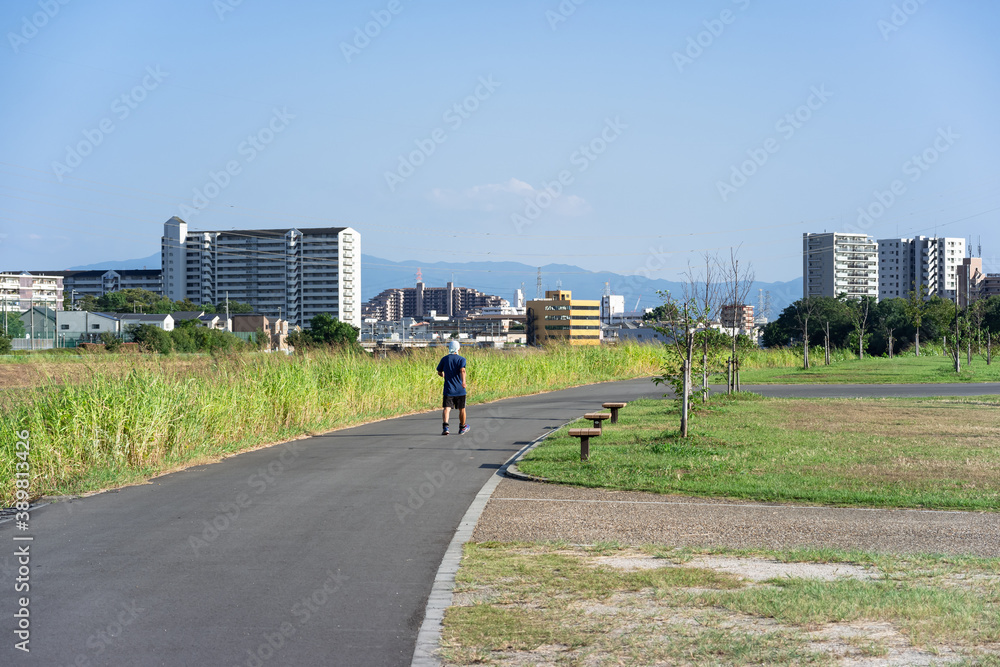 Fototapeta premium 空いている公園の散歩道を、蜜を避けて一人でウォーキングする男性