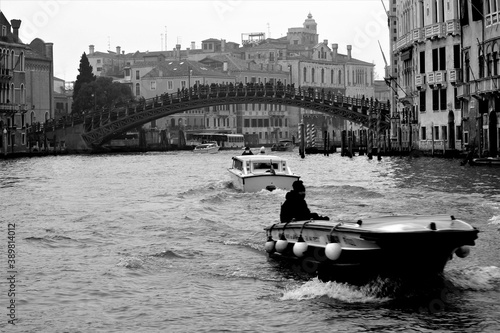 Venice, Italy, December 28, 2018 evocative black and white image of a bridge connecting a canal  in the background with a motorboat in the foreground © massimo