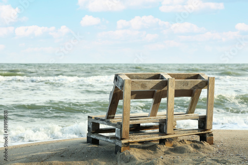 Wooden bench on sandy sea beach  space for text
