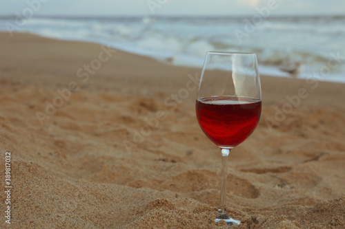 Glass of red wine on sandy sea beach