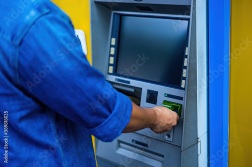 Close-up of man (wearing blue jean), using credit card to withdrawing money from ATM machine. Finance and business concept