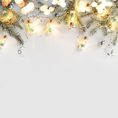 Merry Christmas garland with light on white background with silver decoration, fir branches, confetti, bokeh, light, glitter. Xmas and New Year greeting card, winter holiday. Flat lay, top view