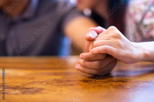 Closeup on two young lovers holding hands at a table  symbol sign sincere feelings  compassion  loved one  say sorry. Reliable person  trusted friend  true friendship concept.