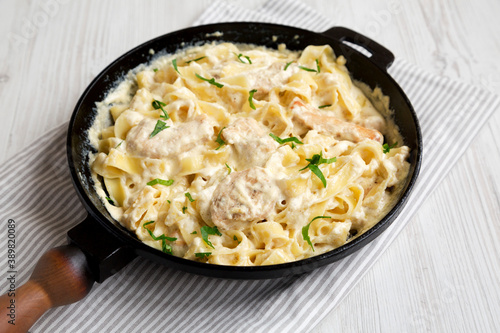 Homemade Chicken Fettuccine Alfredo in a cast-iron pan, side view.
