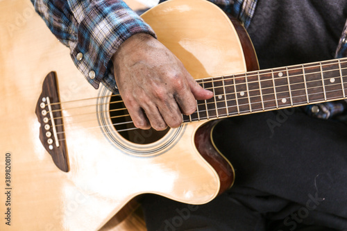Senoir man sitting and playing acoustic guitar.
