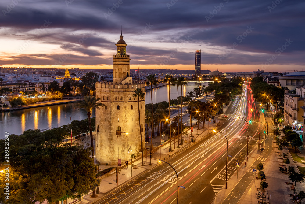 Vista cinematica nocturna de la Torre del Oro de Sevilla con el Río Guadalquivir y Torre Sevilla al fondo