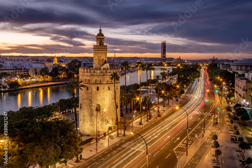 Vista cinematica nocturna de la Torre del Oro de Sevilla con el Río Guadalquivir y Torre Sevilla al fondo