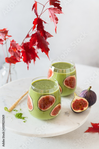 Healthy detox green smoothie with spinach, apple, kiwi and figs in glasses on light background. Side view. Detox menu, dieting, healthy nutrition. Super foods. Matcha green smoothie