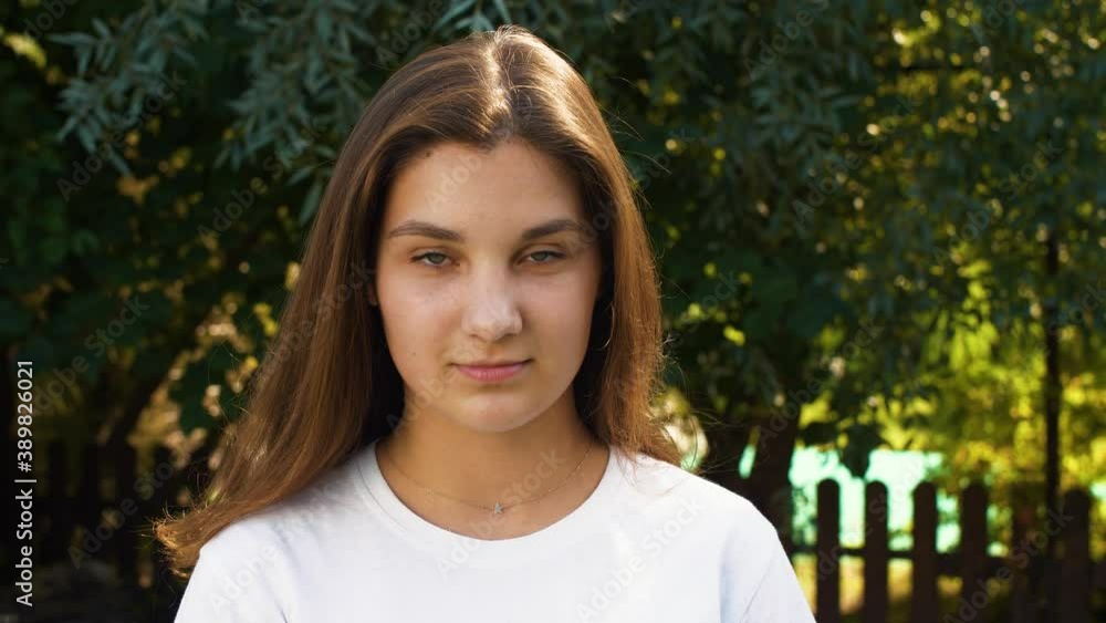 Young caucasian pretty girl lifts her head and looks at the camera, then lowers it again. Street portrait of a teenager. Calm emotion. Young caucasian pretty girl lifts her head and looks at the camera, then lowers it again. Street portrait of a teenager. Calm emotion.