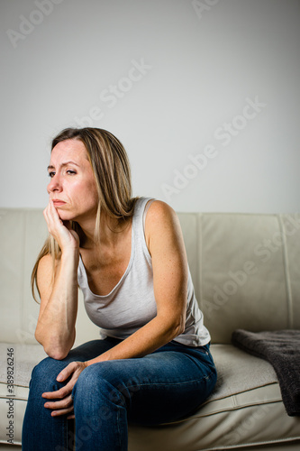 Mid-aged woman touching her cheek/mouth with painful expression because of toothache/dental issue photo