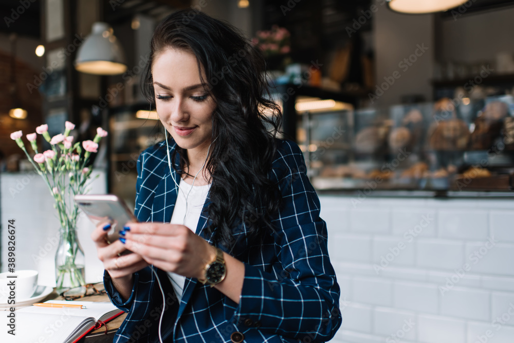 Young woman in earphones with phone chilling in cafe Young woman in earphones with phone chilling in cafe