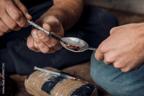 two shabby men preparing drug injection in slums