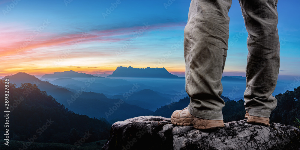 Successful hiker stand on mountain peak rock Successful hiker stand on mountain peak rock