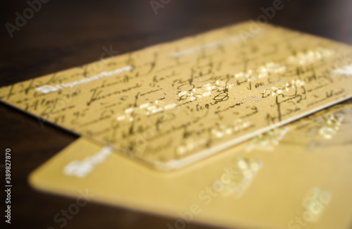 Close-up of two golden credit cards located on a table.