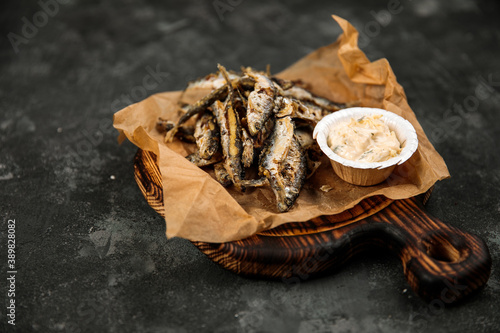 fried vendace with sauce, national Karelian dish, fried fish from Karelia, northern Russian cuisine, fried smelt, on a wooden tray, on a dark background
 photo