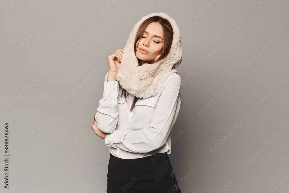 Model girl with perfect makeup in white blouse and fur hood posing in the studio at grey background, isolated Model girl with perfect makeup in white blouse and fur hood posing in the studio at grey background, isolated