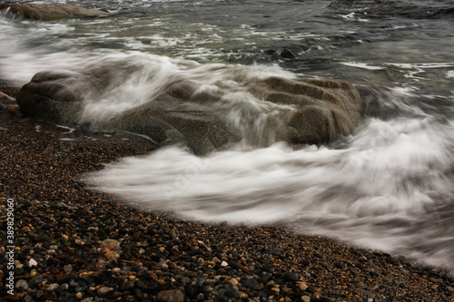 A blurred wave on a rocky beach.