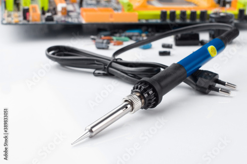 Obraz na płótnie soldering iron on the background of a computer Board and capacitors in soft focus. w salonie