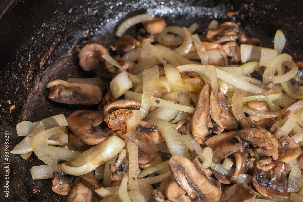 Champignons frying on the pan with onion Champignons frying on the pan with onion
