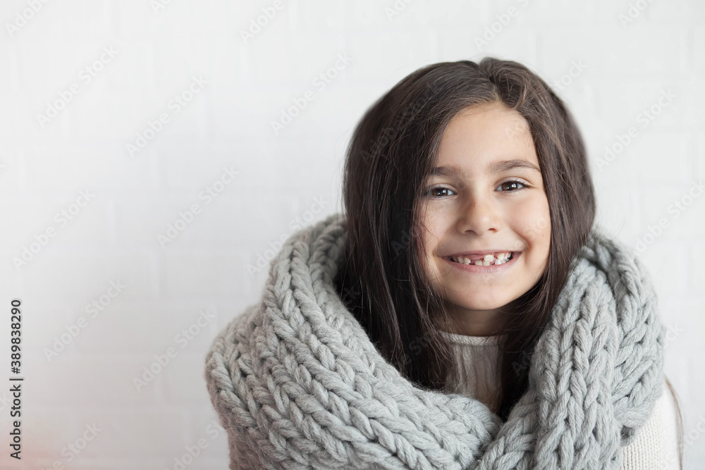 Happy laughing child girl in winter grey knitted scarf at studio. Positive emotions. Happy laughing child girl in winter grey knitted scarf at studio. Positive emotions.