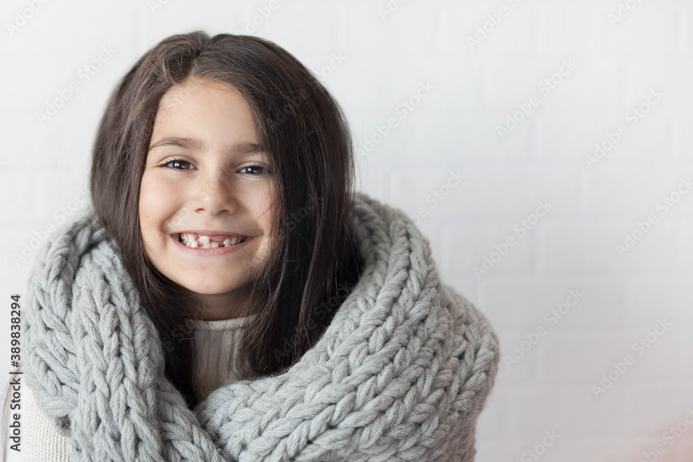 Happy laughing child girl in winter grey knitted scarf at studio. Positive emotions. Happy laughing child girl in winter grey knitted scarf at studio. Positive emotions.