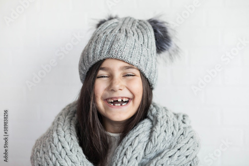 happy laughing child girl in winter knitted hat and scarf hat at studio