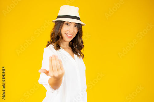 Young woman over isolated yellow background inviting to come with hand. Happy that you came