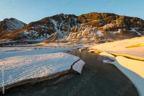 The famous sand beach near Haukland during sunset on the Lofoten islands in Norway on clear winter day with snow-clad mountains and blue sky photo