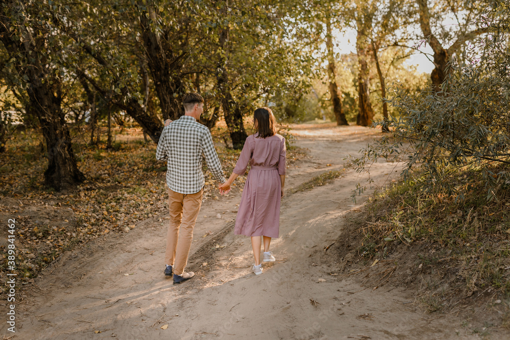 Happy family walking on the road in the park. Father, mother holding baby son on hands and going together. Rear view. Family Ties concept. Happy family walking on the road in the park. Father, mother holding baby son on hands and going together. Rear view. Family Ties concept.