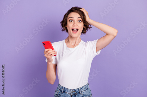 Photo portrait of shocked amazed girl with bob hair holding cellphone staring touching head isolated on vivid violet color background