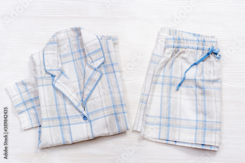 Folded warm white pajamas with blue checks or stripes on white wood photo