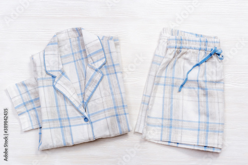 Foto Folded warm white pajamas with blue checks or stripes on white wood