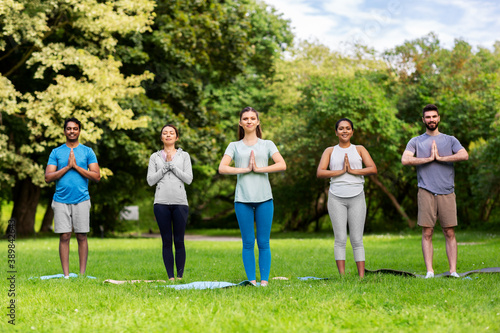 fitness  sport and healthy lifestyle concept - group of happy people doing yoga at summer park