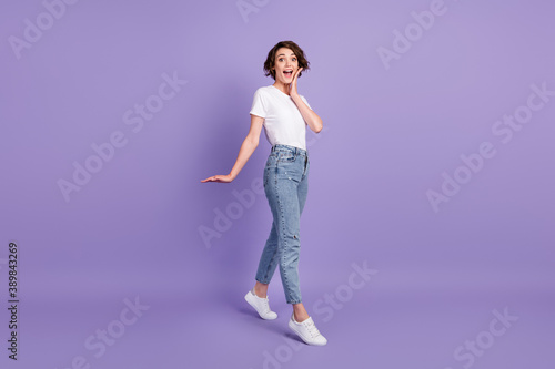 Full length body size photo of amazed girl walking touching cheeks wearing casual outfit isolated on bright violet color background