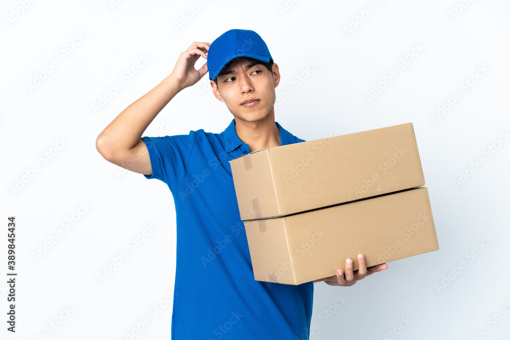Delivery Chinese man isolated on white background having doubts while scratching head Delivery Chinese man isolated on white background having doubts while scratching head