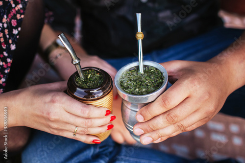 Yerba mate tea in bombilla. Special metal straw. Sout America popular hot drink. Couple drinking healthy herbal beverage. Engagement outdoor picnic.