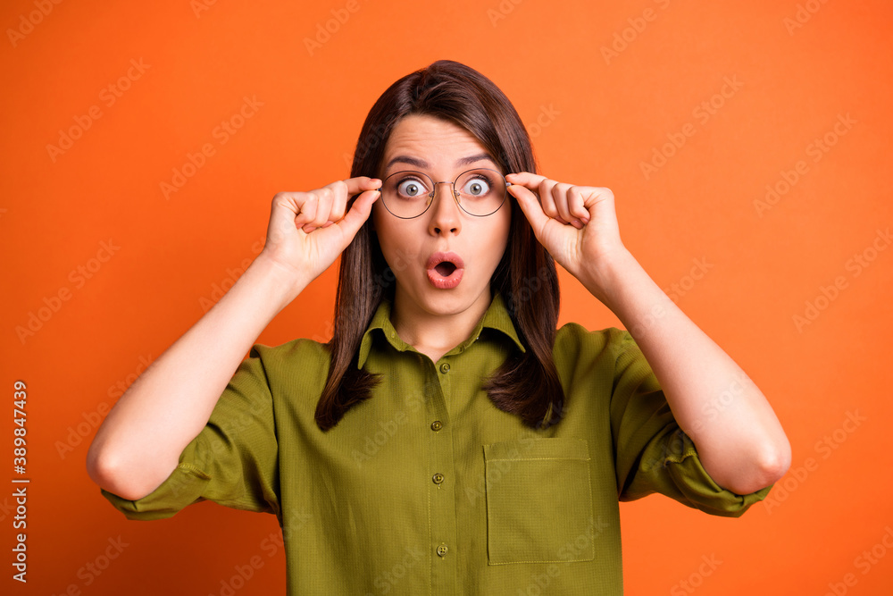 Photo portrait of amazed stressed female freelancer touching glasses opened mouth staring isolated on vibrant orange color background Photo portrait of amazed stressed female freelancer touching glasses opened mouth staring isolated on vibrant orange color background