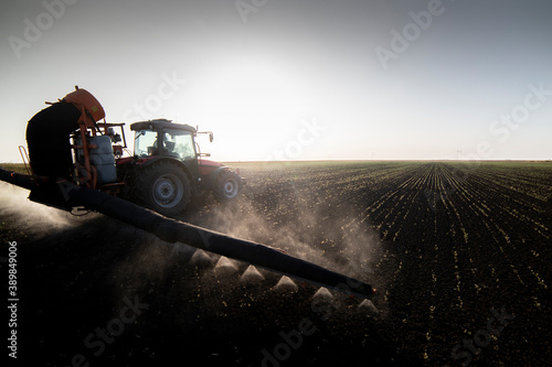 Tractor spraying pesticides on field with sprayer