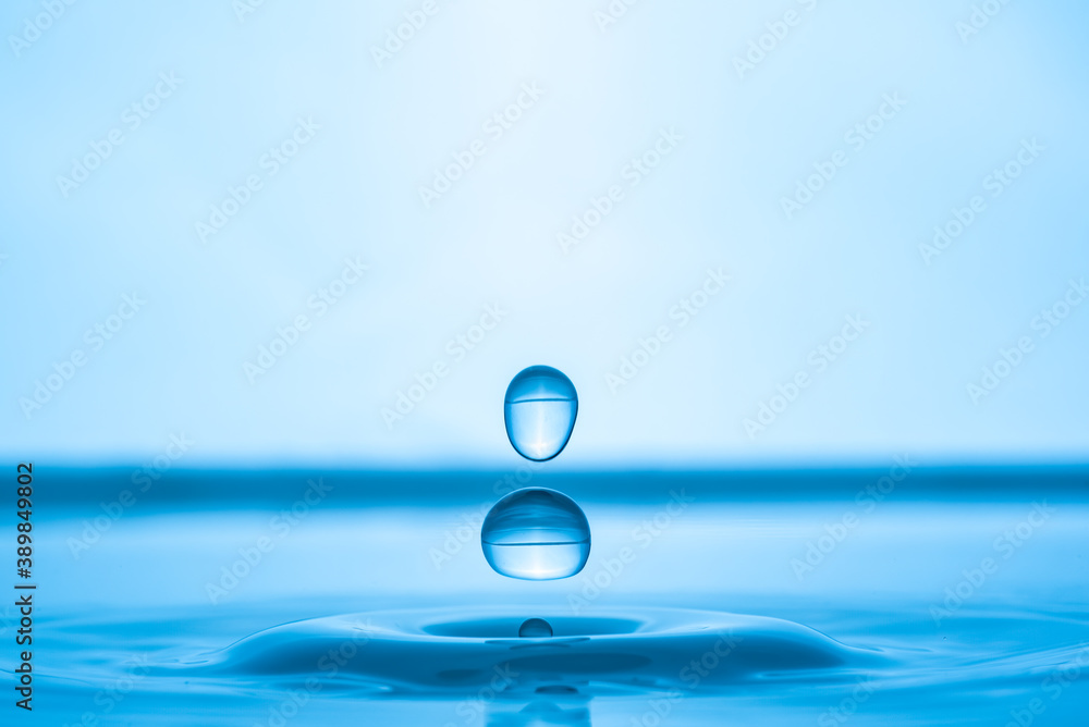 Water drop splashing into blue water surface Water drop splashing into blue water surface