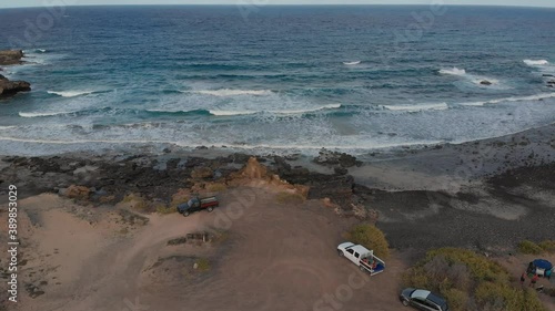 Dark rocky shore tilt towards a blue wave and cloud-filled horizon. photo