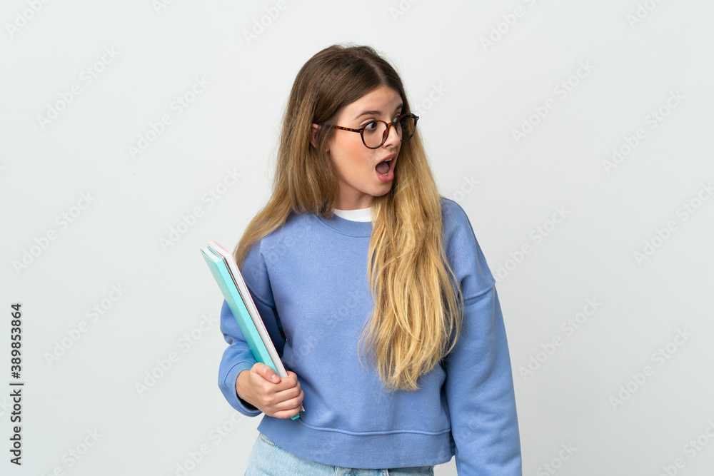 Young blonde student woman isolated on white background doing surprise gesture while looking to the side Young blonde student woman isolated on white background doing surprise gesture while looking to the side